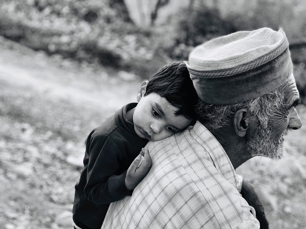 boy leaning beside an old man